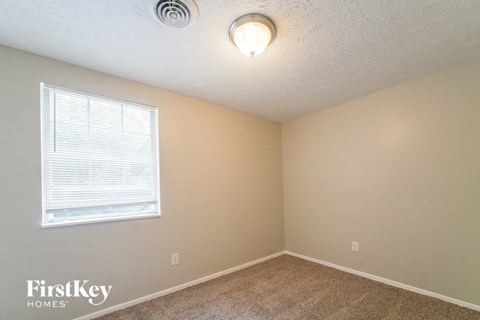 a bedroom with a large window and a carpeted floor