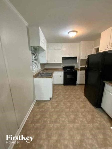 a kitchen with a black refrigerator and a sink