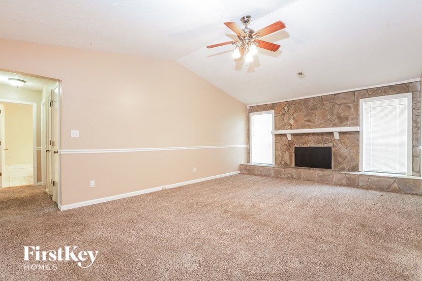 an empty living room with a fireplace and a ceiling fan