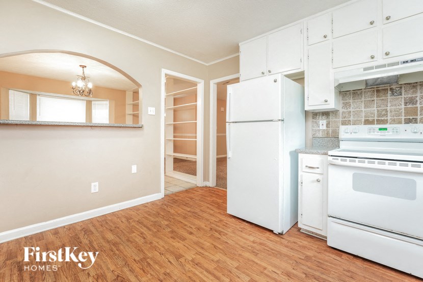 a kitchen with white appliances and a wooden floor