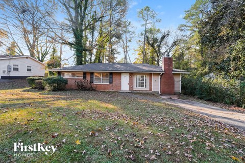 a white and brick house with a brick chimney and a yard