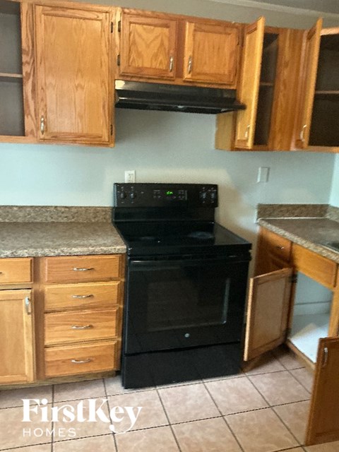 A kitchen with a black oven and wooden cabinets.