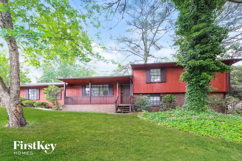 a red house with a green lawn and trees