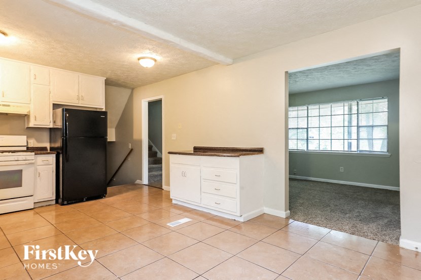 an empty kitchen with a black refrigerator and a sink