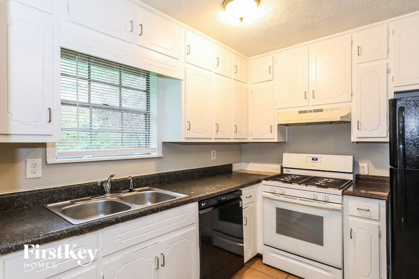 a kitchen with white cabinets and black counter tops