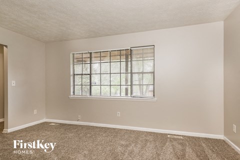 the living room of a home with a window and carpet