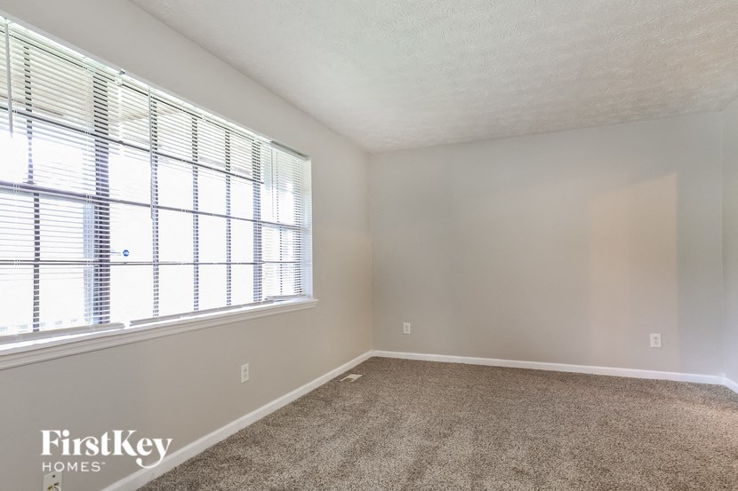 an empty room with a large window and carpet