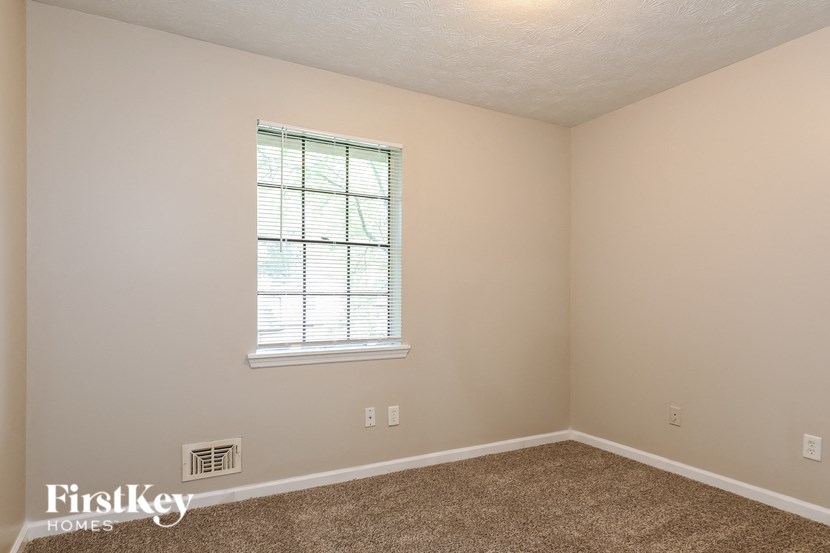 a bedroom with a window and a carpeted floor