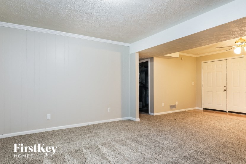 the living room of a house with carpet and a door to a closet