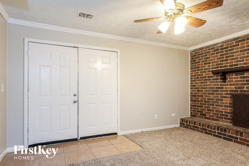 a living room with a brick fireplace and a ceiling fan
