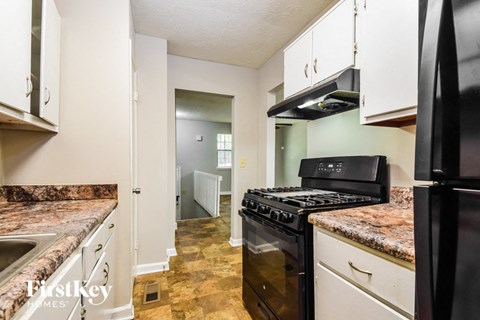 a kitchen with black appliances and white cabinets and granite counter tops