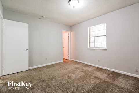 a living room with carpet and white walls and a window