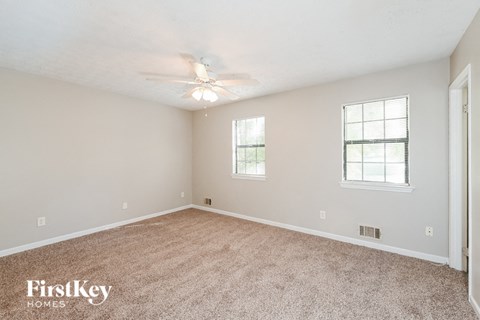 a spacious living room with carpet and a ceiling fan
