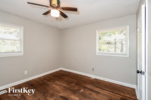 an empty bedroom with a ceiling fan and wood flooring