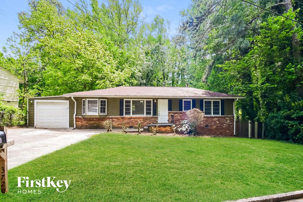 a small brick house with a lawn and a driveway