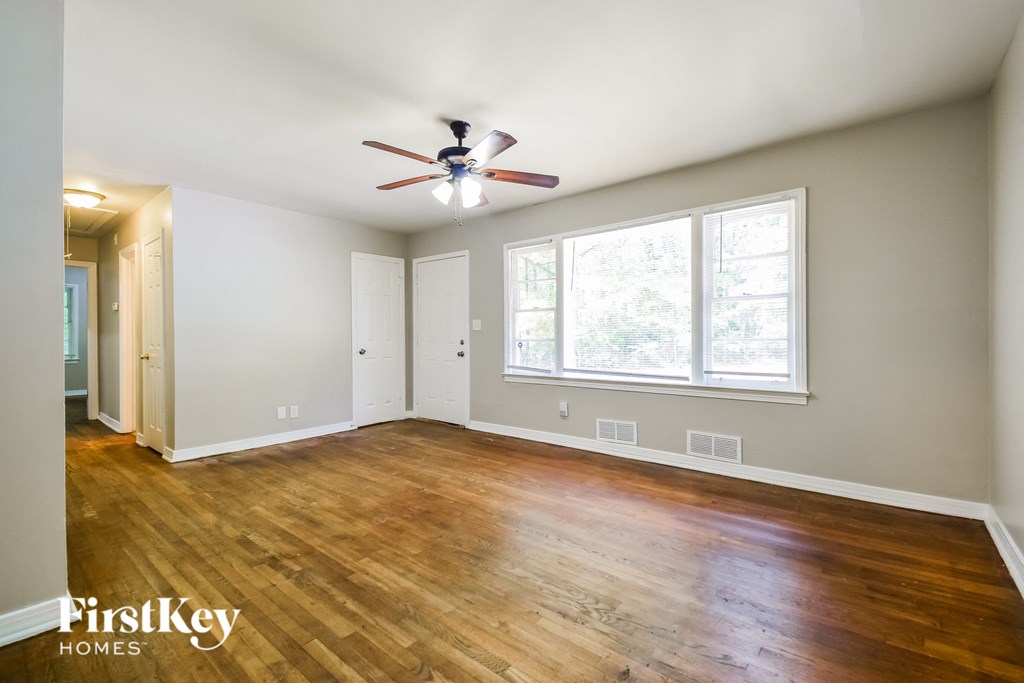 an empty living room with wood floors and a ceiling fan