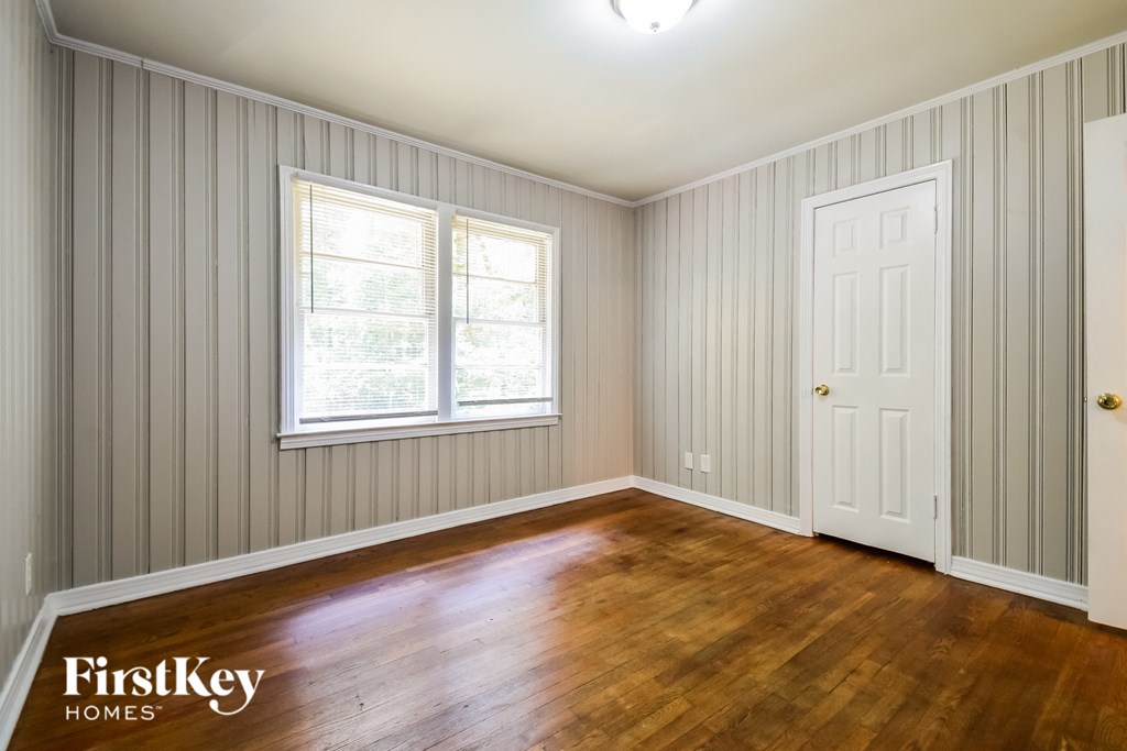 a bedroom with wood floors and a white door and window