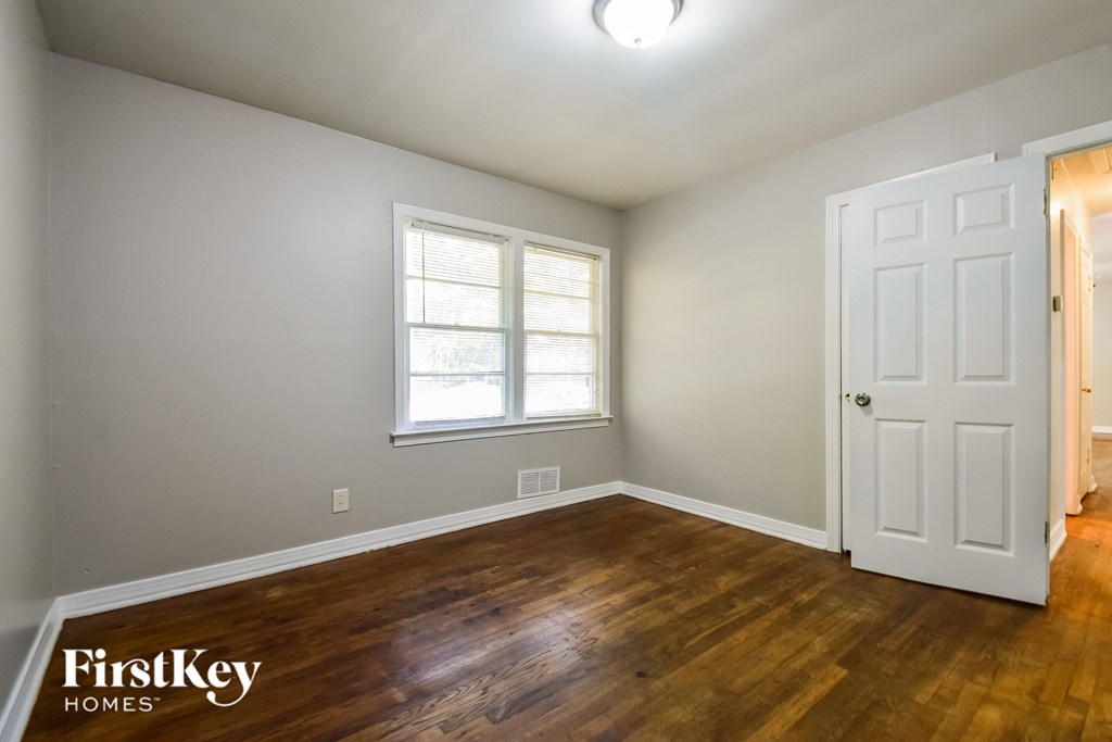a bedroom with hardwood flooring and a white door