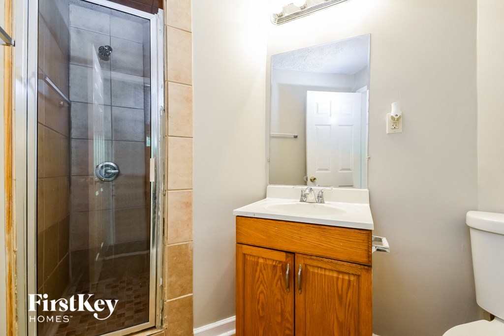 a bathroom with a shower sink and mirror and a toilet