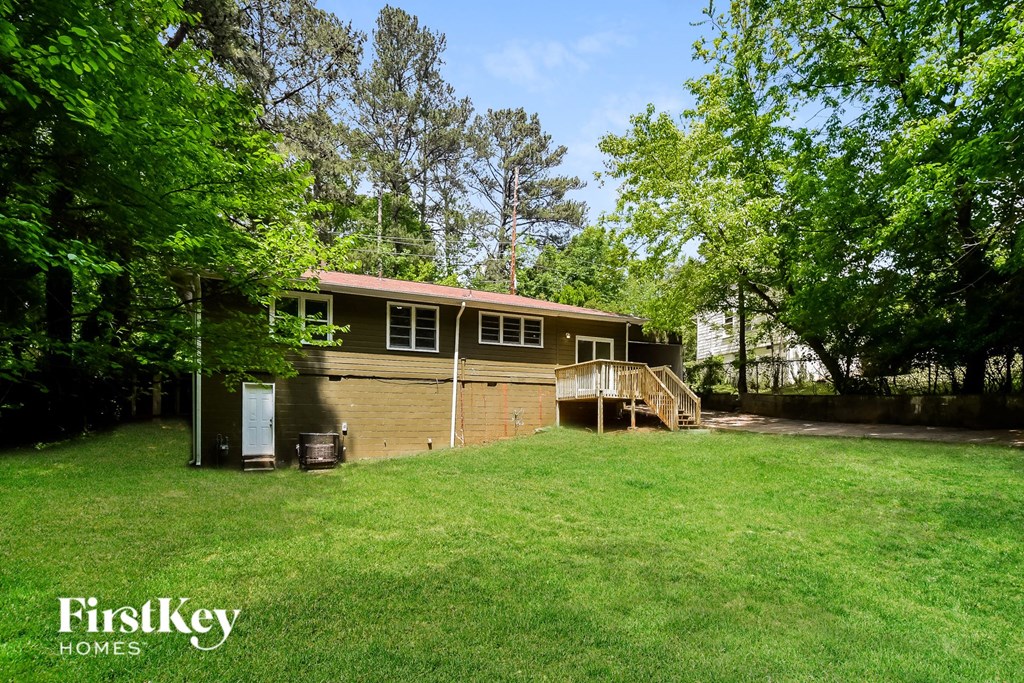 the front of the house with a big lawn and trees