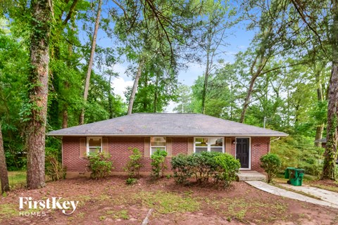 a small brick house in the woods with trees