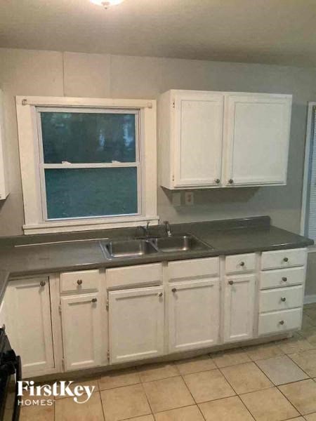 A kitchen with white cabinets and a black countertop.