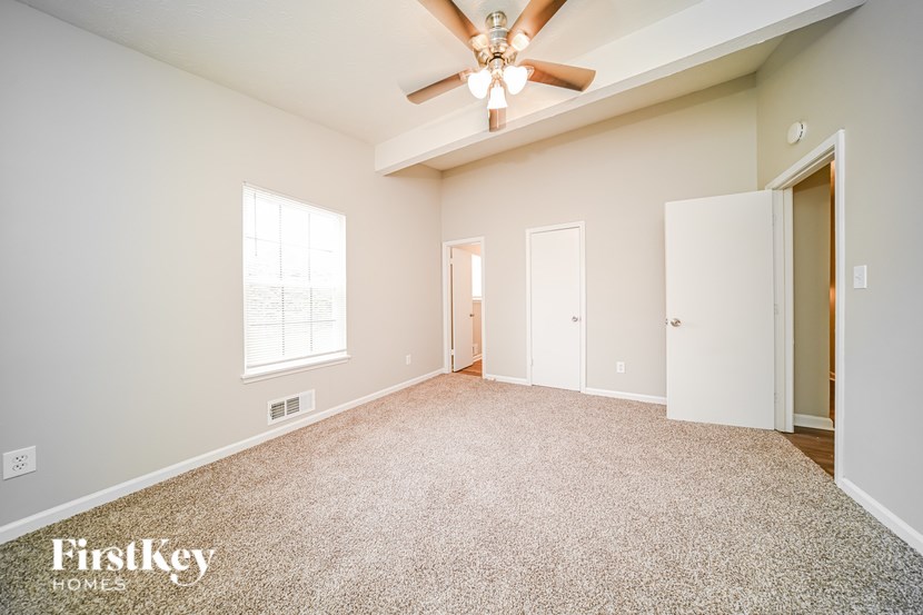 A spacious room with a ceiling fan and carpeted floor.
