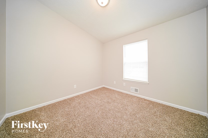 A room with a carpeted floor and a window letting in light.