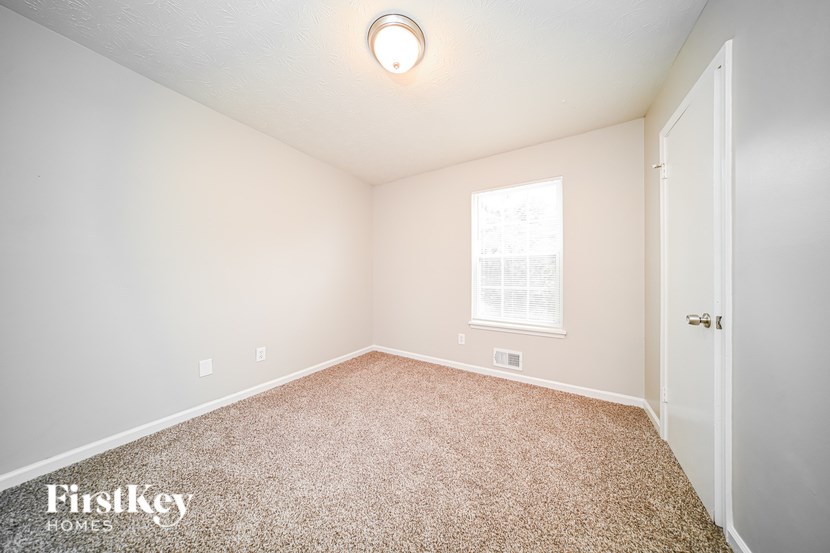 A room with a carpet floor and a window with blinds.