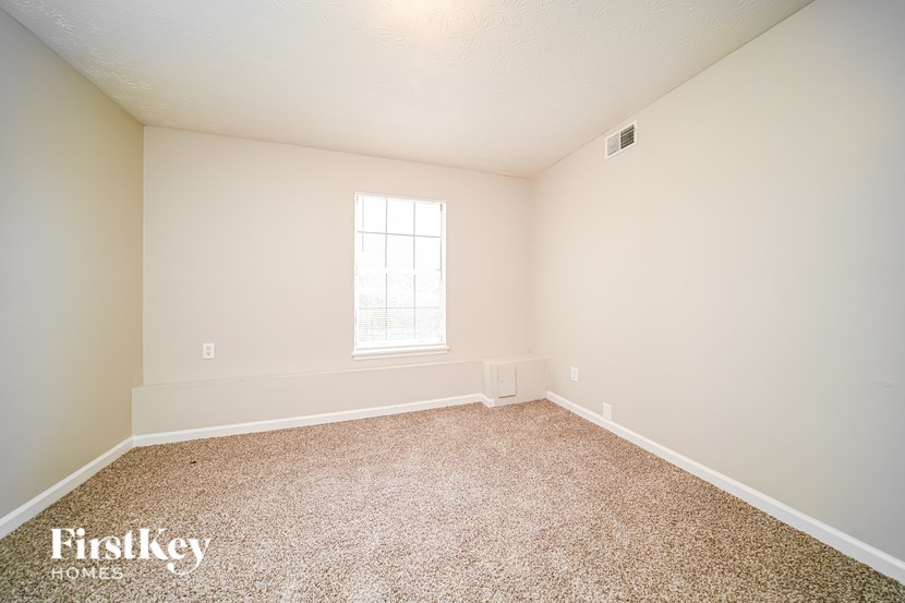 A room with a window and a carpeted floor.