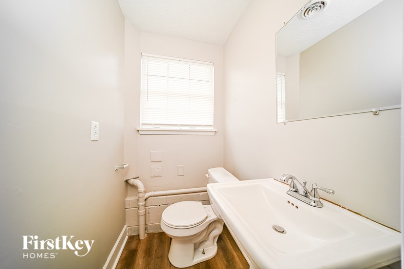 A white bathroom with a toilet, sink, and mirror.