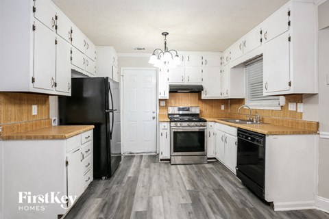 a kitchen with white cabinets and black appliances