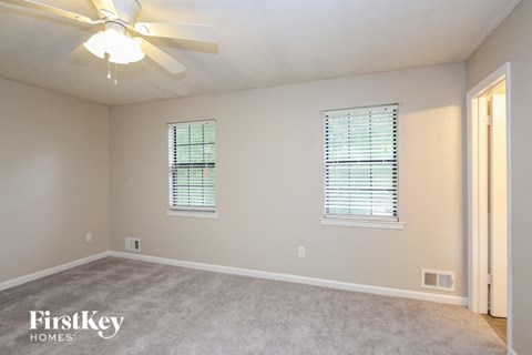 a bedroom with a ceiling fan and two windows