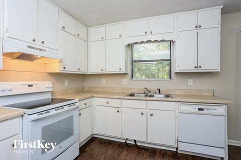 A white kitchen with a stove top oven and a dishwasher.