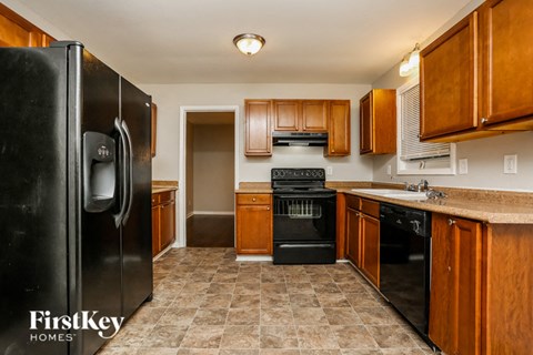 A kitchen with a black fridge and wooden cabinets.