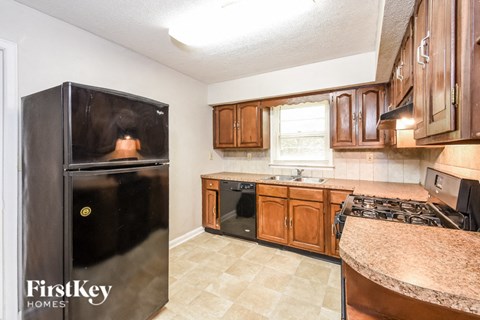 a kitchen with wooden cabinets and a black refrigerator