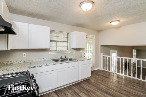 the kitchen of an apartment with white cabinets and a sink and a stove