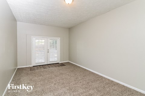 a spacious living room with carpet and a door to a balcony
