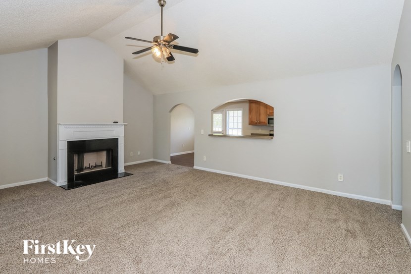 an empty living room with a fireplace and a ceiling fan