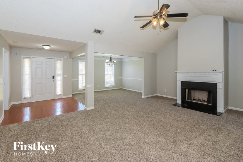 an empty living room with a fireplace and a ceiling fan