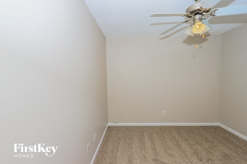 a bedroom with a ceiling fan and a carpet