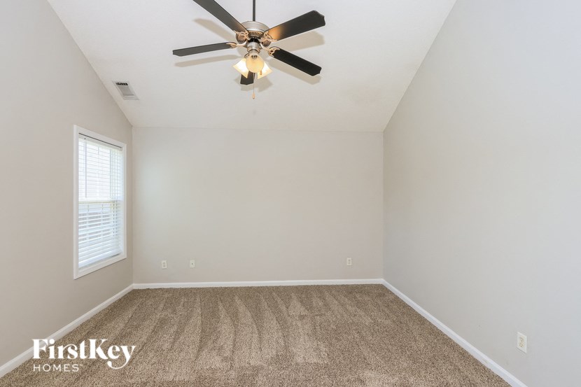 an empty living room with a ceiling fan