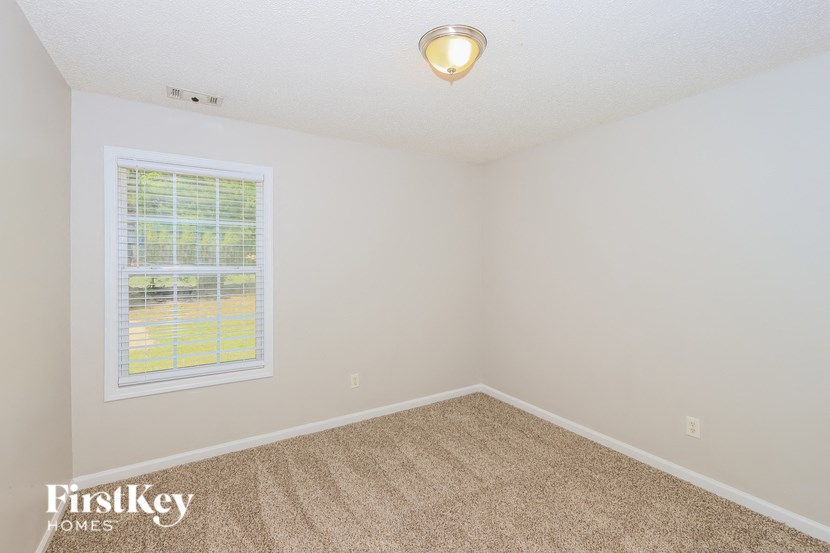 an empty bedroom with a window and carpet