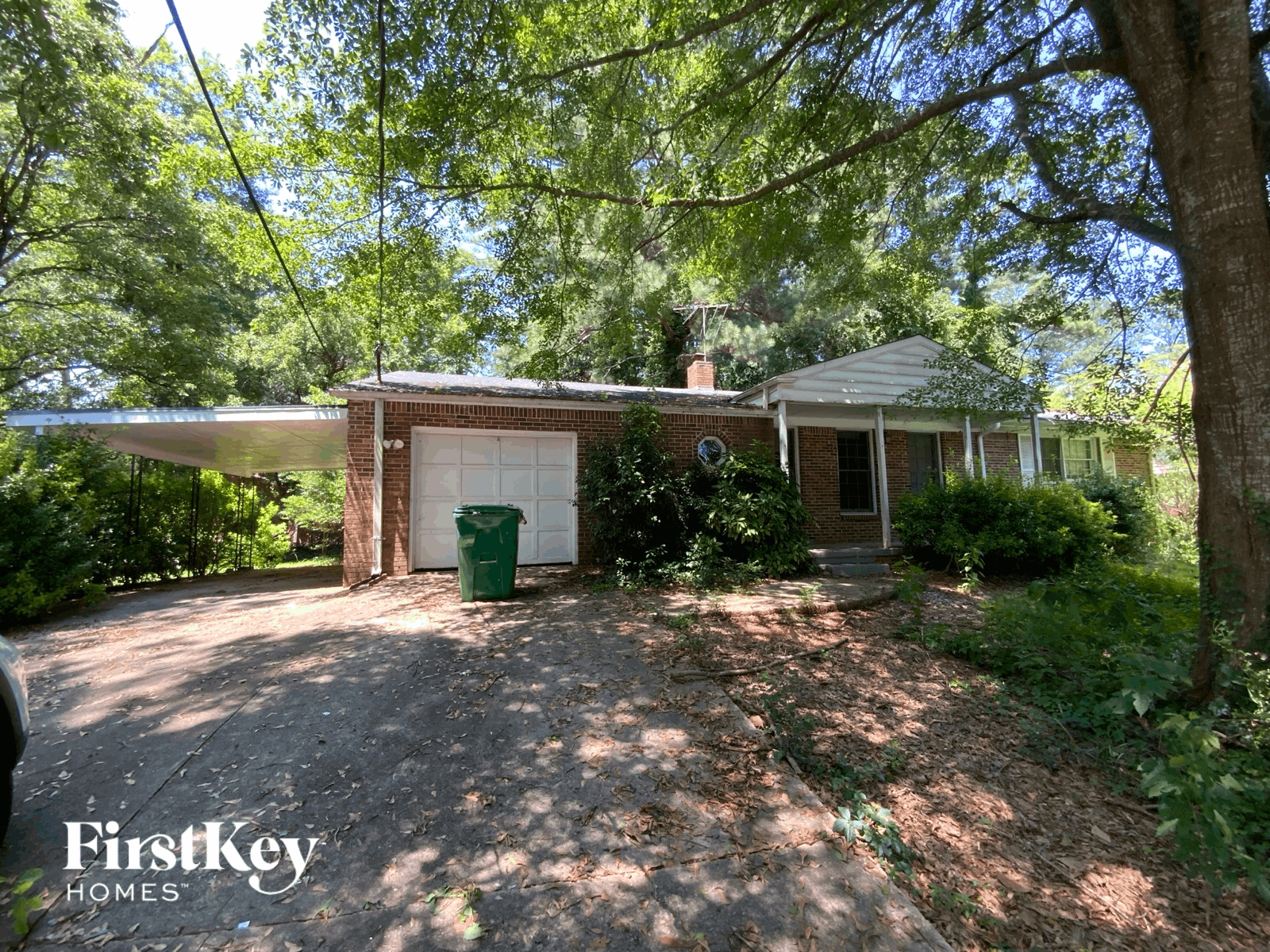 A house with a driveway and a green trash can.