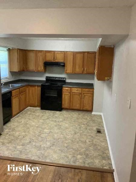 A kitchen with wooden cabinets and a black stove top oven.