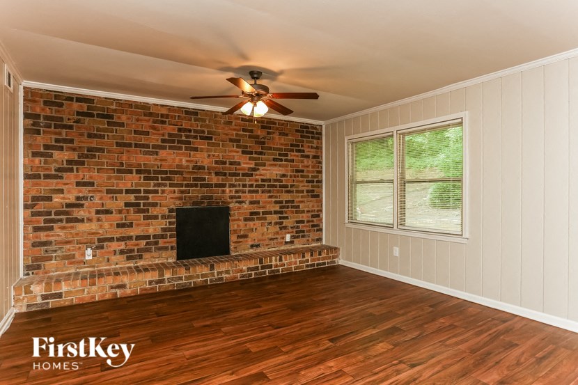 a living room with a brick fireplace and a ceiling fan
