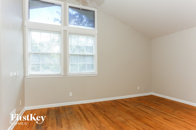 a room with a wooden floor and three windows