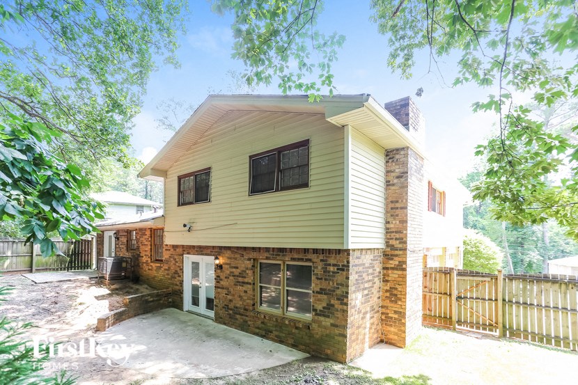 a small yellow house with a brick wall and a fence