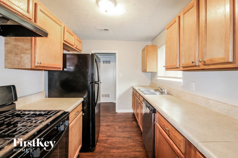 A kitchen with wooden cabinets and a black fridge.