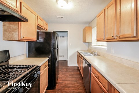 A kitchen with wooden cabinets and a black fridge.